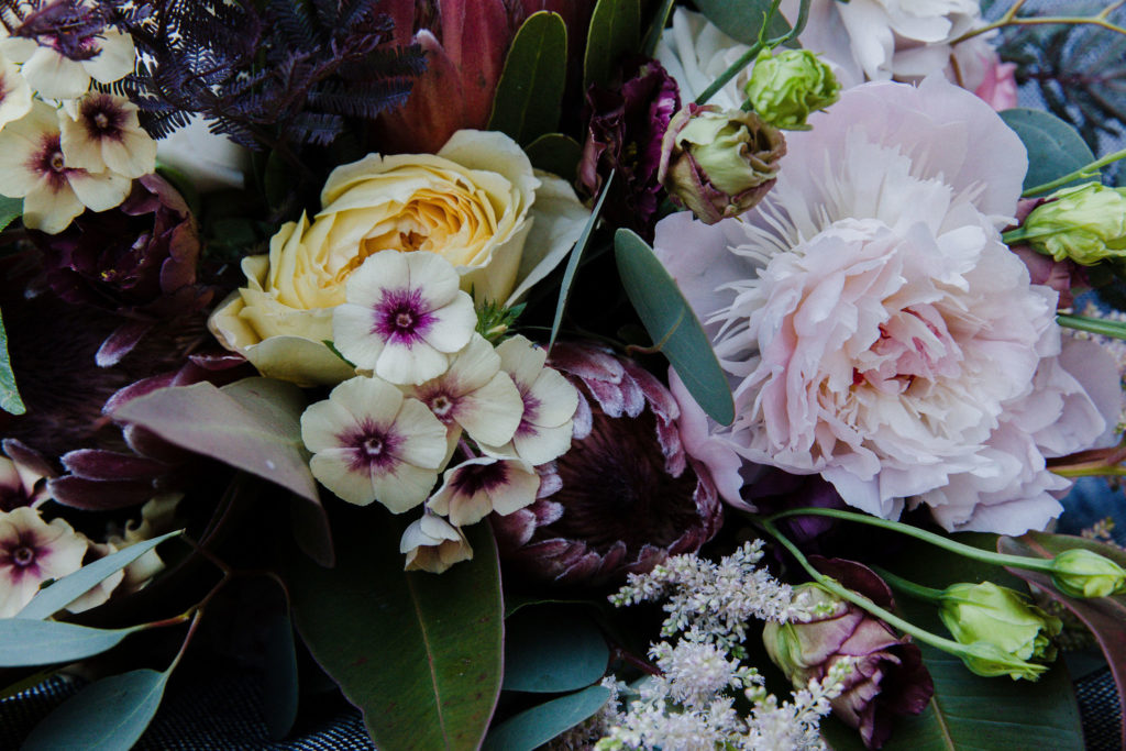 Wedding flower details for a colorful bohemian wedding at Salvage One in Chicago — flowers included protea, lisianthus, garden roses, peonies, ranunculus, and more.