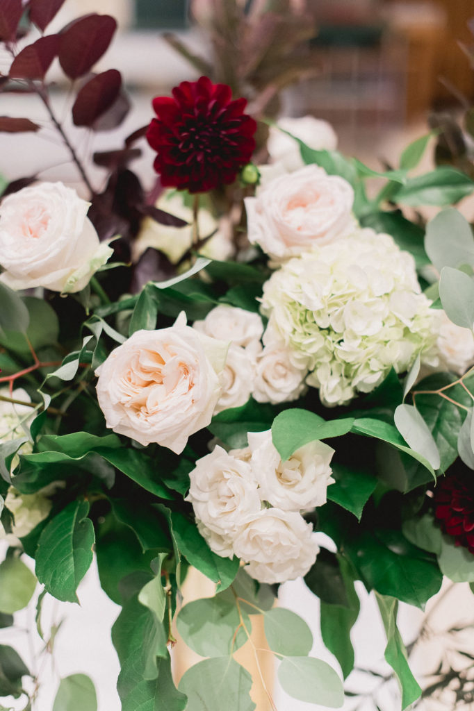 Fall wedding arrangement floral details: blush garden roses, pale green hydrangea, eucalyptus, burgundy dahlias, and spray roses.