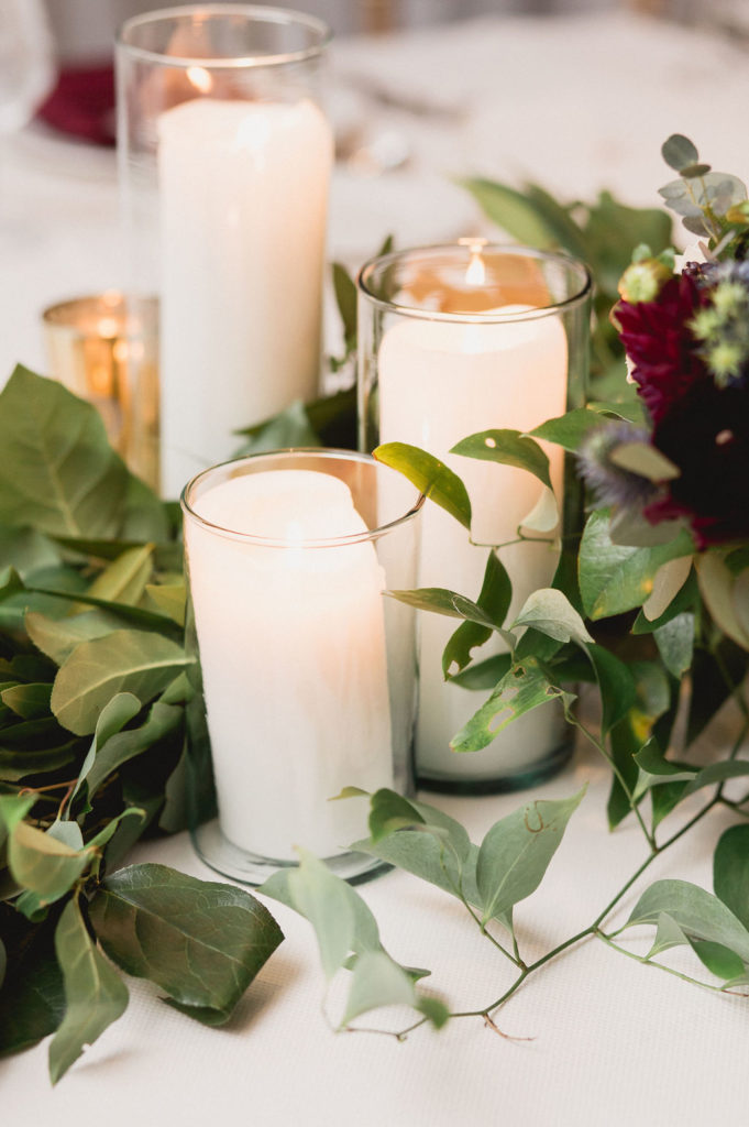 Class details from the reception of a traditional fall wedding: pillar candles and foliage.