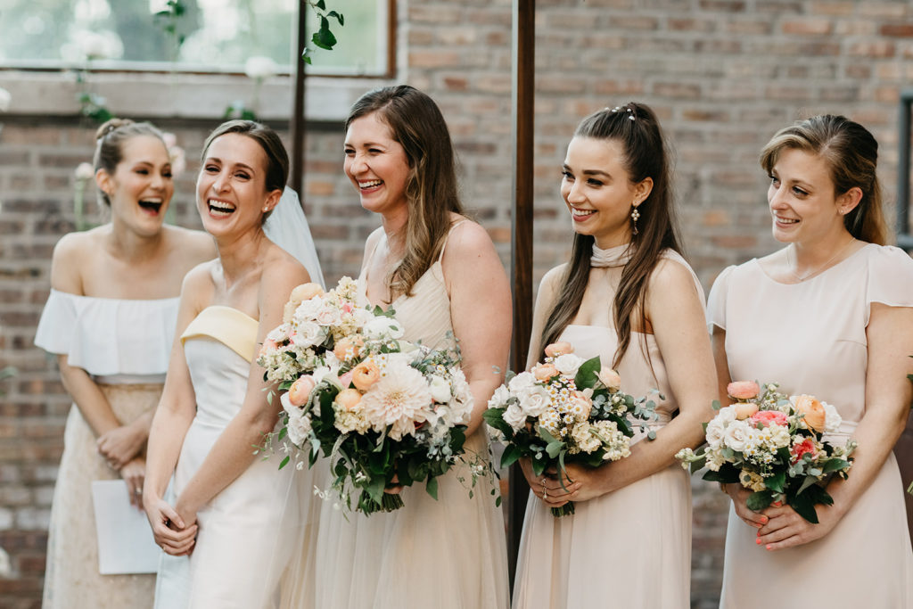 Bride and bridesmaid bouquets with bright pink garden roses and ranunculus, peach ranunculus, and white dahlias, roses, ranunculus, and daisies.