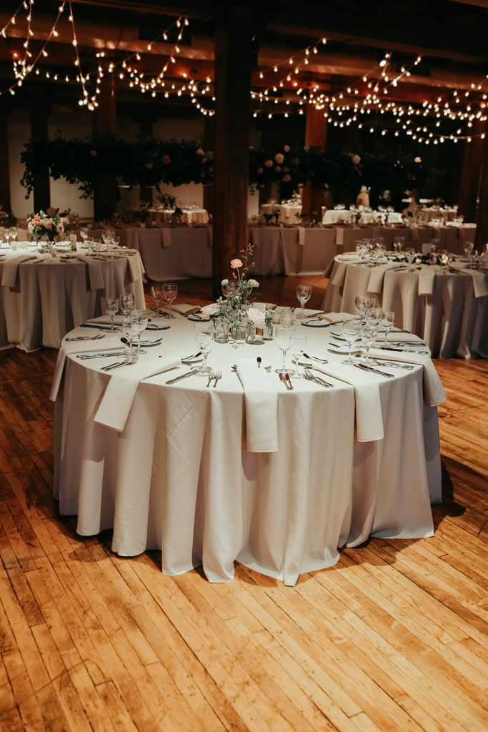 Bridgeport Art Center's Skyline Loft in Chicago wedding reception with rustic tables, cafe lights, and ranunculus and rose centerpieces. 