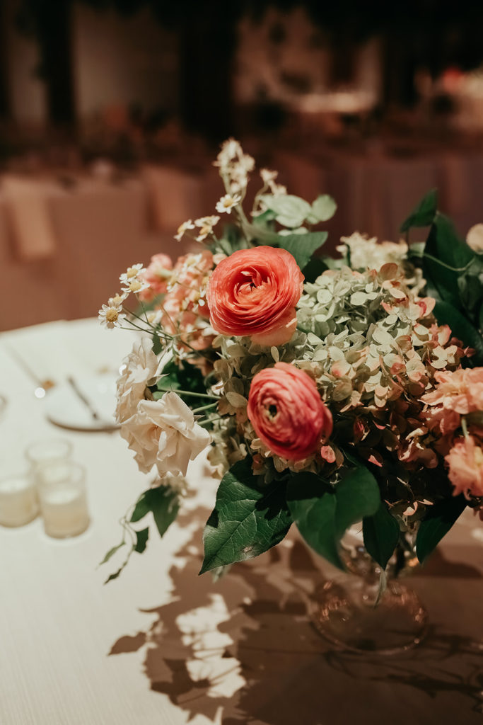 Elegant table arrangement of bright pink ranunculus, stock, pale green hydrangea, majolica roses, and daises for a late summer wedding reception held at Bridgeport Art Center's Sculpture Garden.