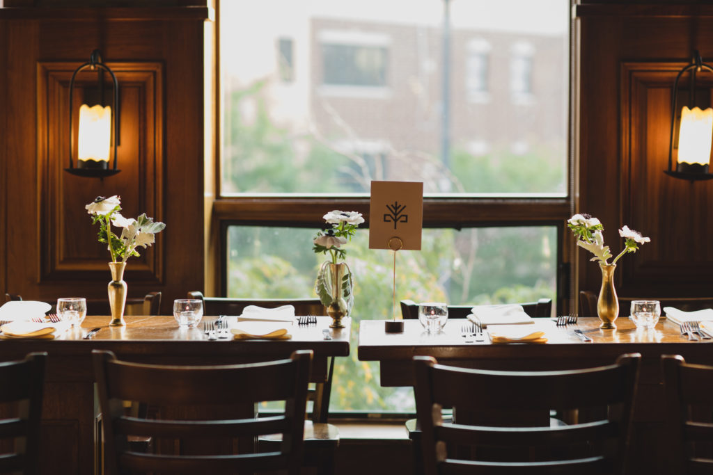 Minimal table arrangements of anemones in brass vases for a wedding ceremony at Revolution Brewing Chicago.