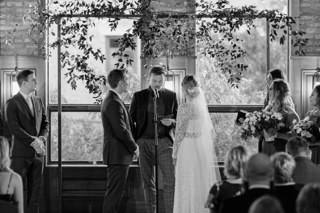 Black and white wedding ceremony with minimal, industrial altar decorated in foliage at Revolution Brewing Chicago.