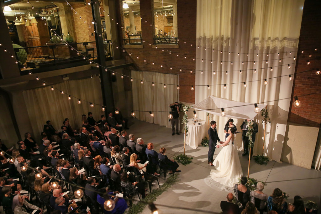 Cafe lights, high ceilings, an elegant chuppah with garden roses and eucalyptus, and exposed brick gave an urban romantic environment to this fall wedding at Artifact Events in Chicago.