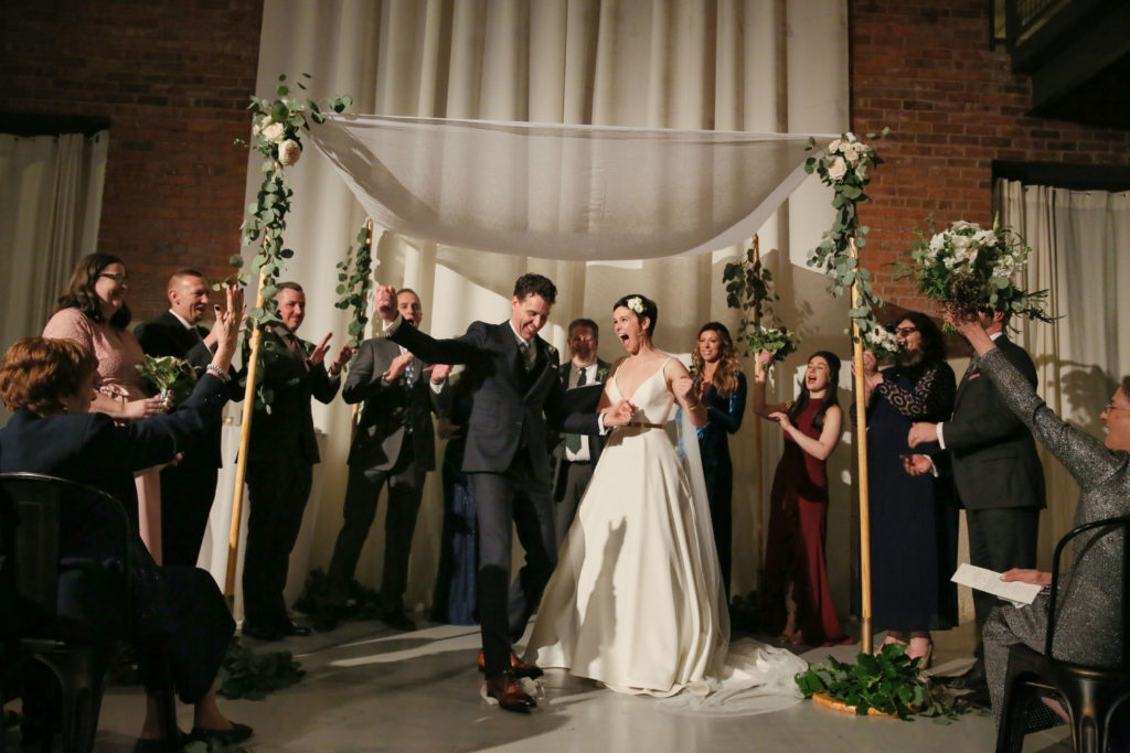 Cafe lights, high ceilings, an elegant chuppah with garden roses and eucalyptus, and exposed brick gave an urban romantic environment to this fall wedding at Artifact Events in Chicago.
