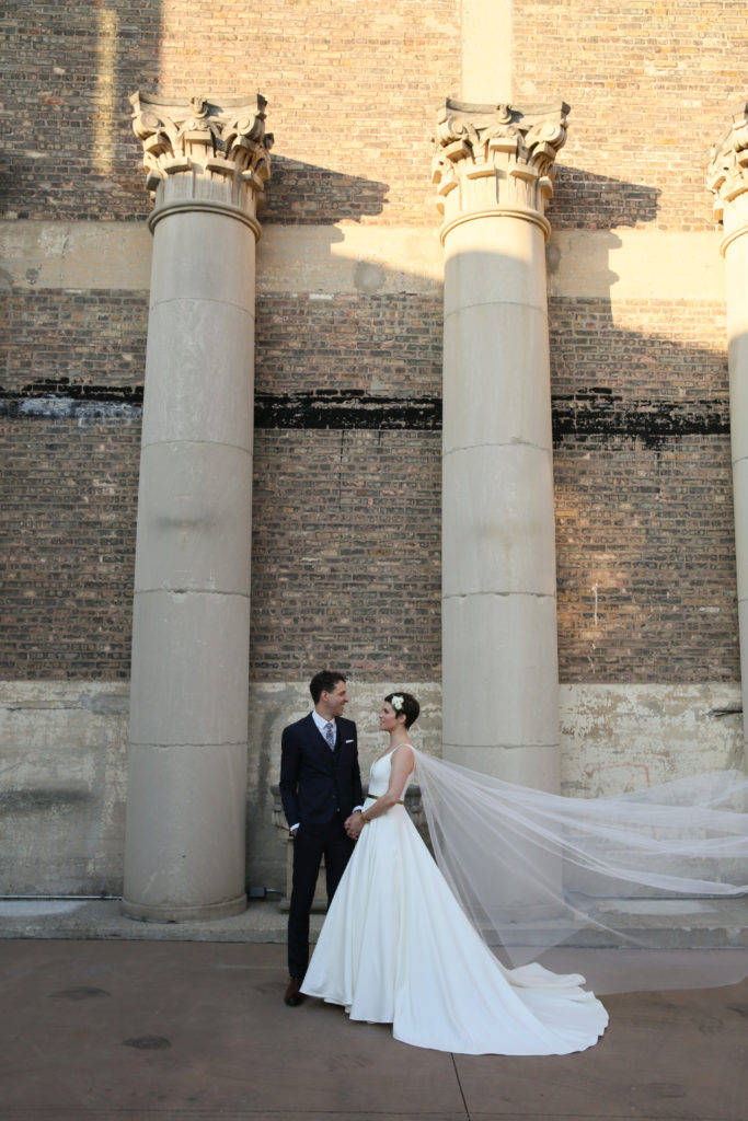 Formal bride and groom portrait with stone column background and long veil for a wedding at Artifact Events in Chicago.