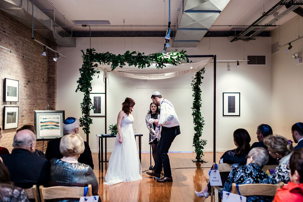 A winter Jewish wedding ceremony with a foliage-lined chuppah at Floating World Gallery.