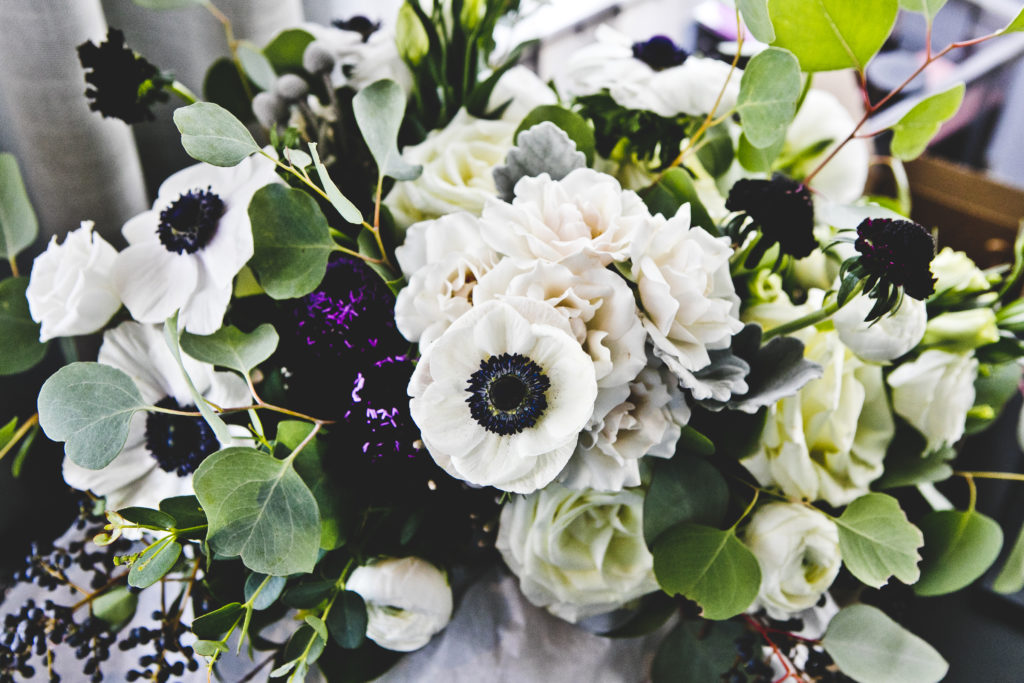 Bridal bouquet comprised of ivory majolica roses, garden roses, anemone with deep plum scabiosa, berries, and eucalyptus and dusty miller for a Greenhouse Loft wedding.