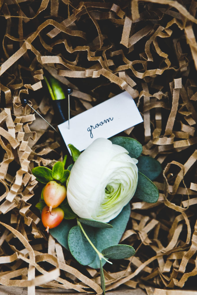 A classic ivory ranunculus boutonniere with peach hypericum berries and eucalyptus. 
