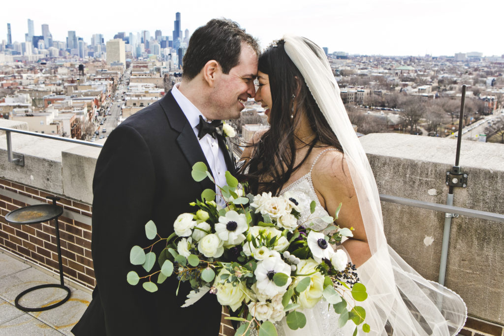 Bride and groom looking over Chicago's skyline, with a loose and gardeny monochromatic anemone, garden rose, and eucalyptus bouquet.