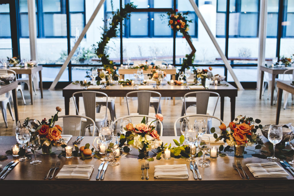 Flower-filled ceremony and reception at greenhouse loft, with colorful arrangements of orange garden roses, coral ranunculus, hypericum berries, hydrangea, protea, and lots of eucalpytus!