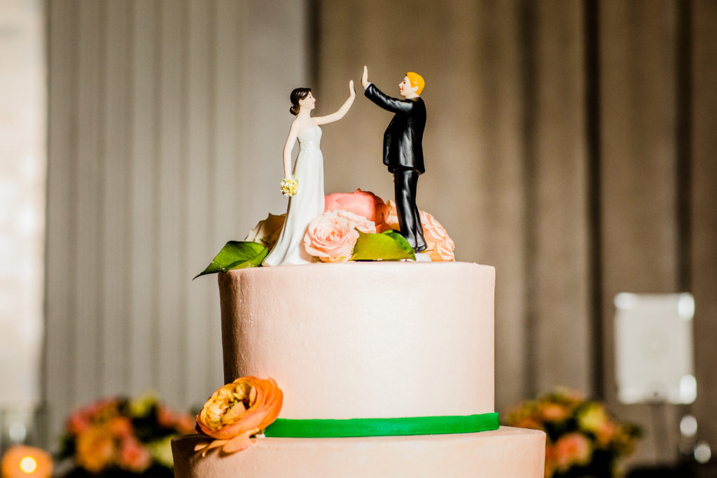 Quirky coral and green wedding cake with high-fiving figurinese for a spring wedding in peach at W City Center in Chicago.