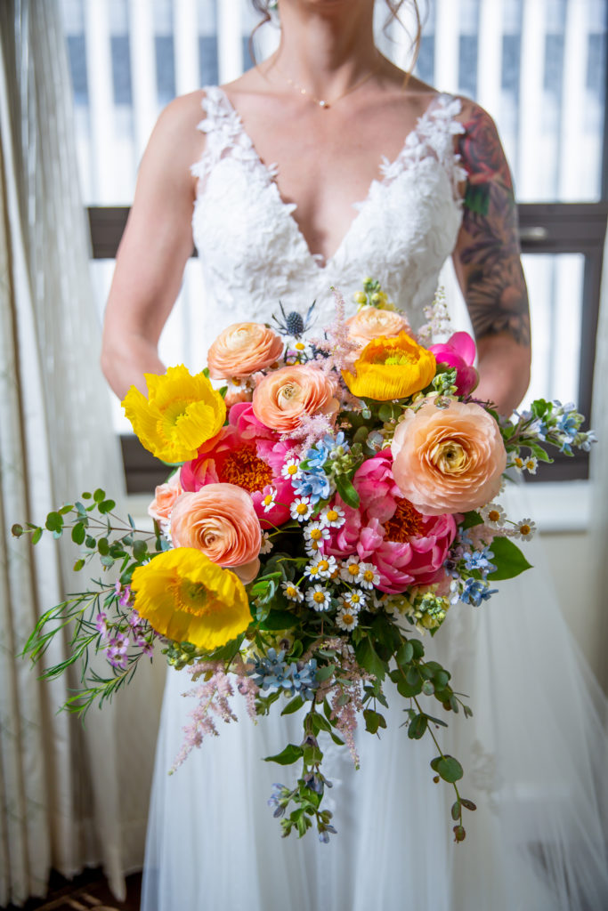 Bridal bouquet of bright colorful spring flowers, including peonies, ranunculus, poppies, and tweedia.