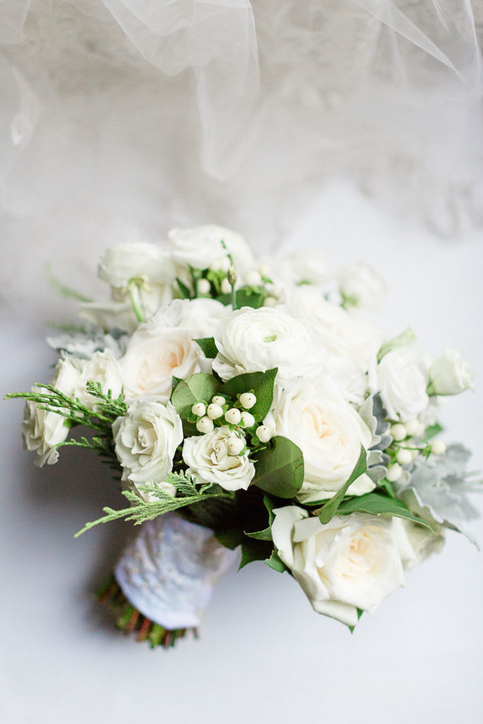 Classic white and green for the bridal bouquet, with white garden roses, ranunculus, berries, dusty miller, and a touch of cedar. 