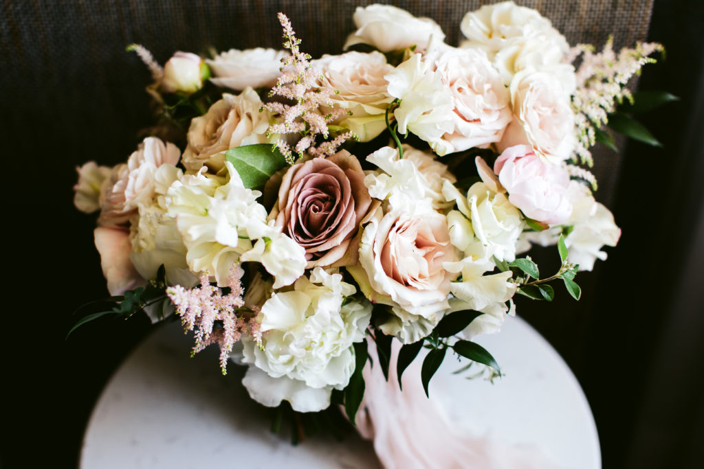 Classic bridal bouquet in ivory and blush with peonies, ranunculus, garden roses, and astilbe. 