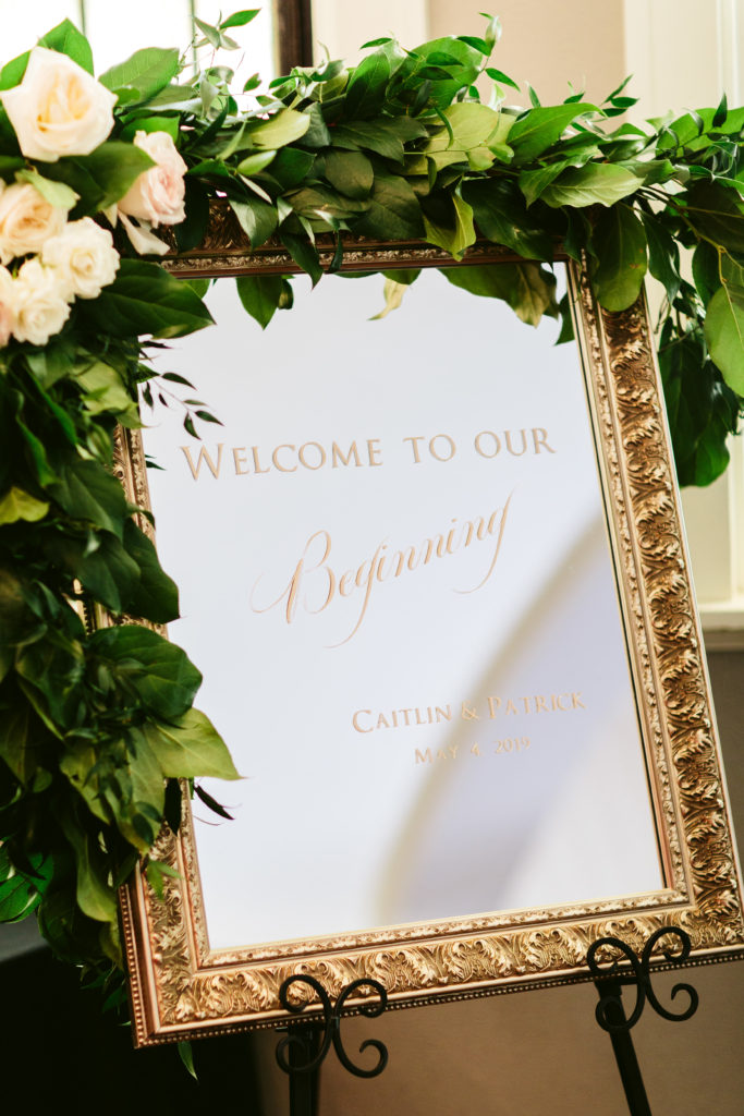 Lush foliage wraps around a gilded mirror with accents of garden roses for this couple's spring wedding.