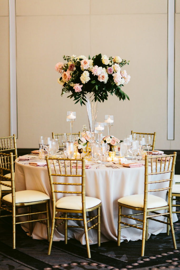 Tall wedding reception arrangement in clear vases with pink peonies, mauve, blush, and ivory garden roses, and hydrangea.