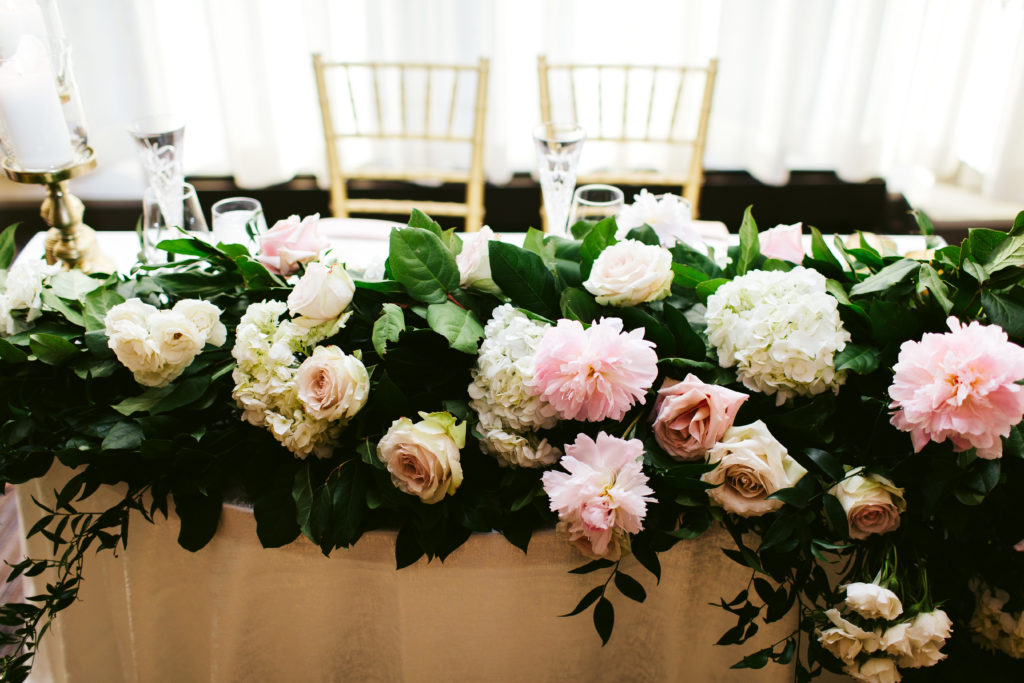 The couple's sweetheart table for their spring wedding featured lush pink peonies, garden roses, and white hydrangea.