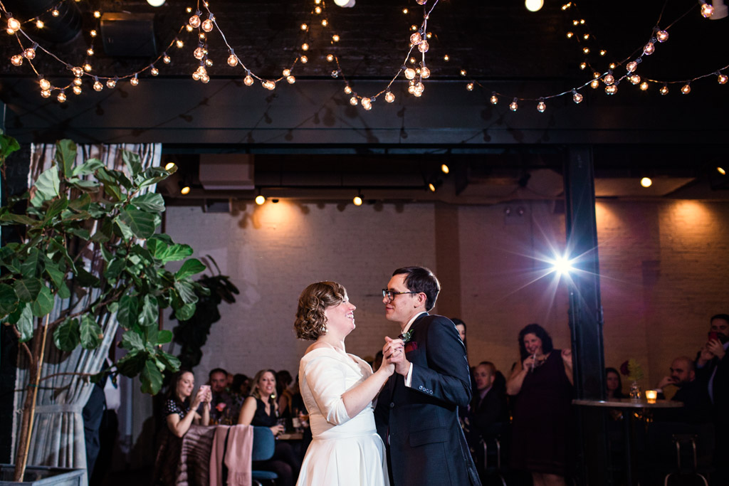 Bride and groom smile at each other while sharing a dance at their fall wedding at The Herbarium.